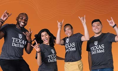 Four students from Dell Med's Class of 2027 gather for a celebratory group portrait. Each student is wearing a Dell Med t-shirt and is doing the "Hook 'Em" gesture.