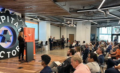 A woman delivers remarks to an audience as part of Texas Health Catalyst's Roundup and Rodeo event hosted at capital factory.