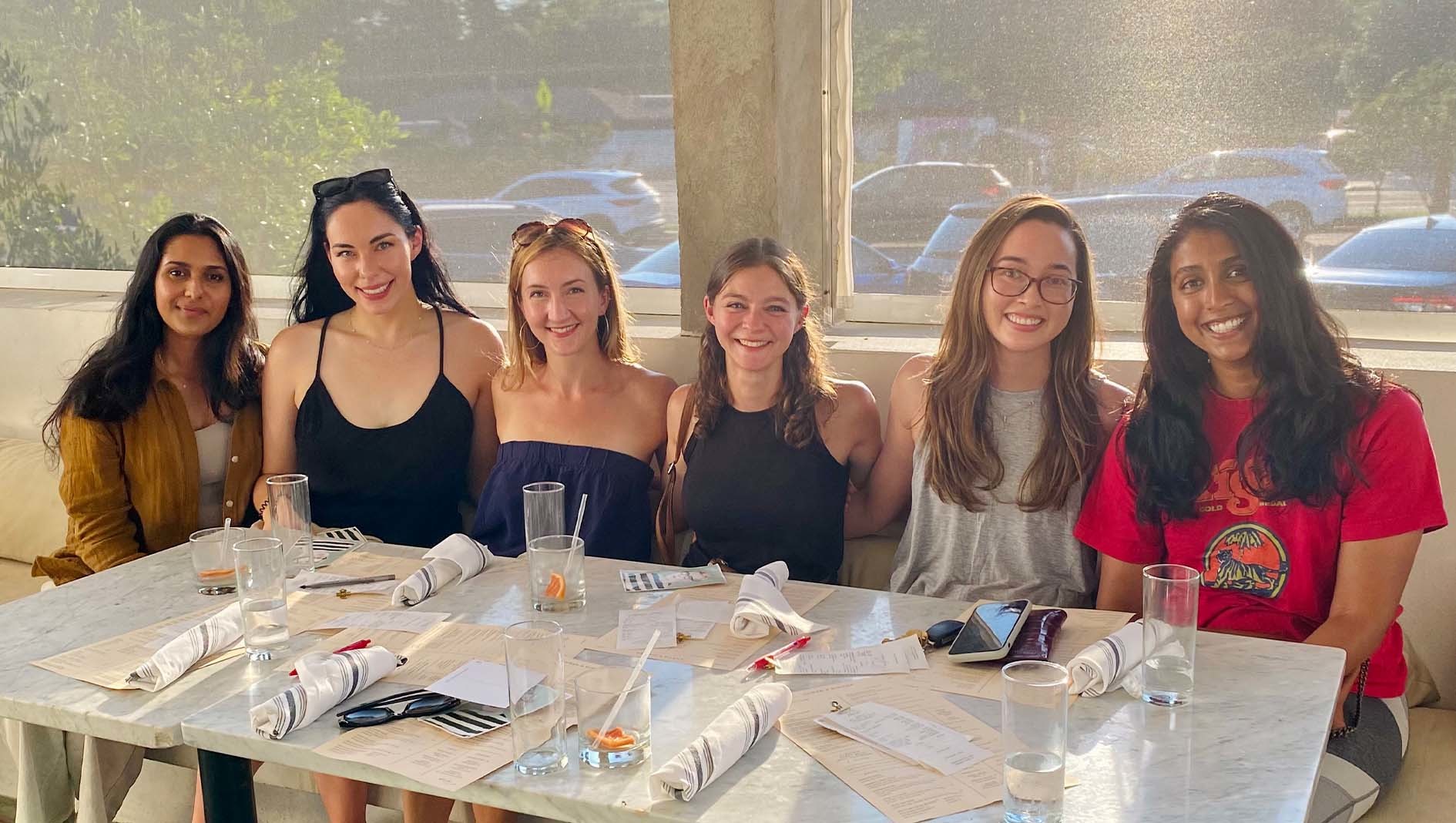 Six members of Dell Med's Transitional Residency at a restaurant table.