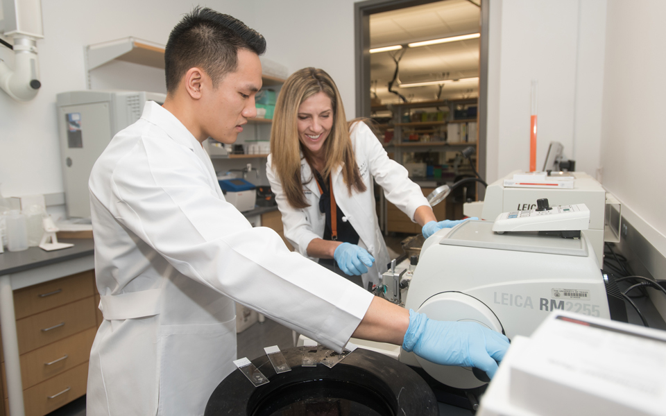 Two medical students working with a research machine in a lab.