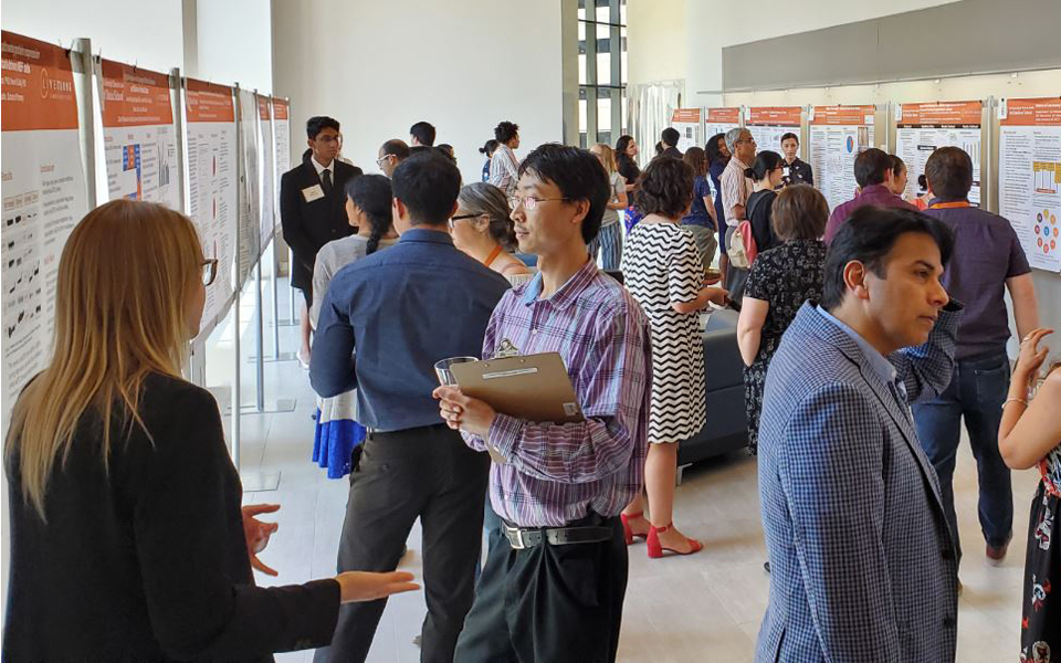 Groups of people walking around reading research posters at a poster presentation event.