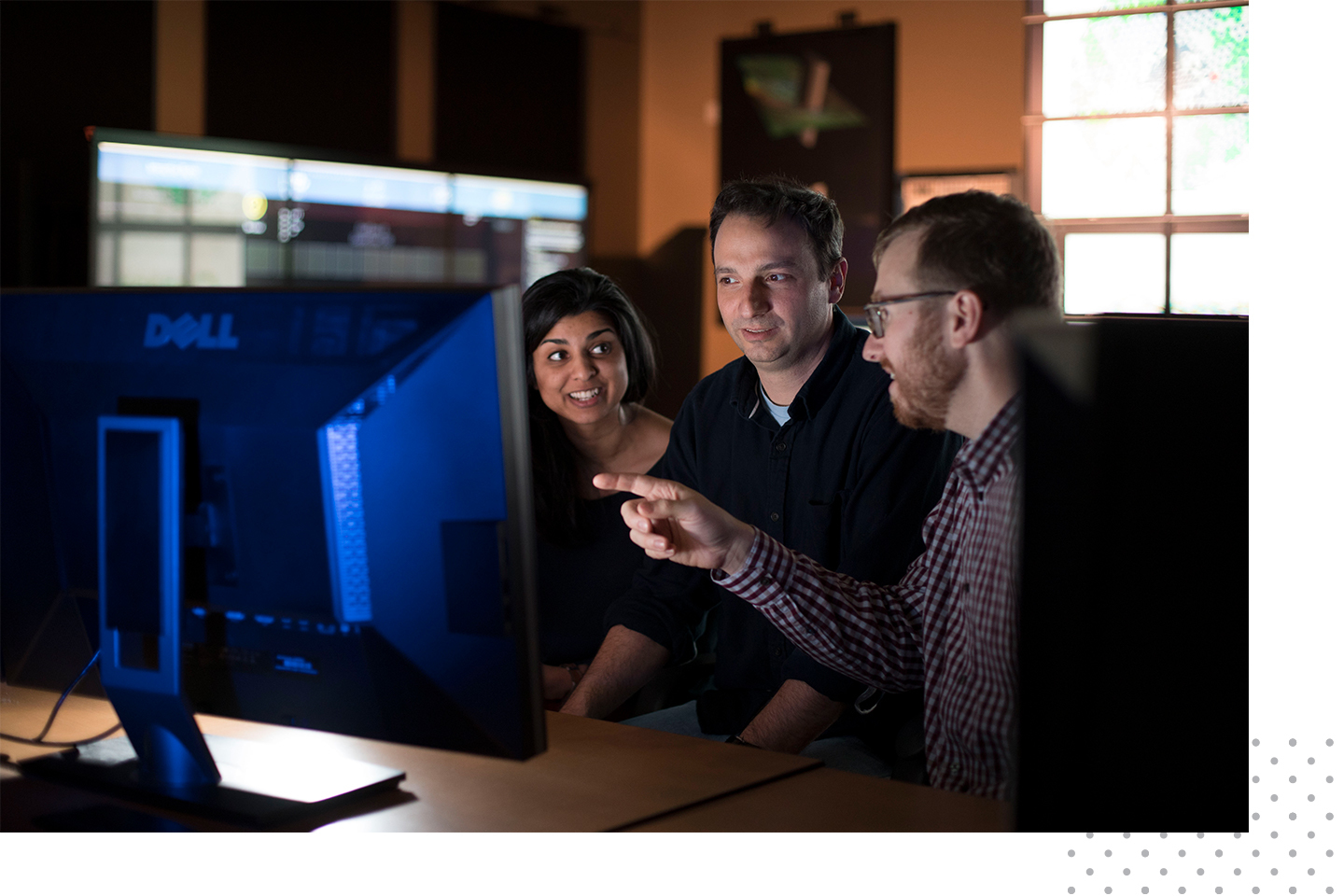 A woman and two men looking at research on a computer screen.