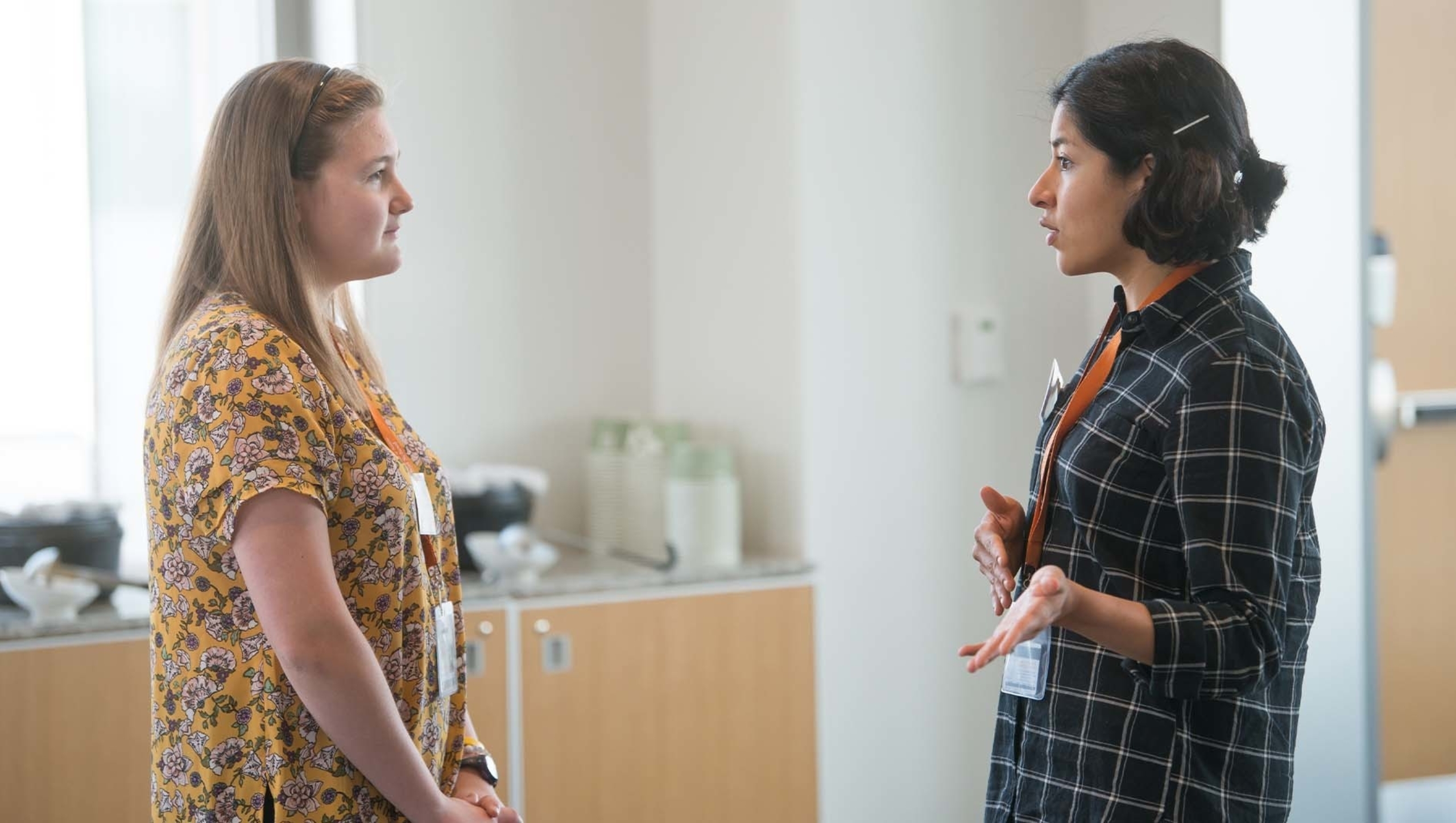 Two women standing in front of each other talking.