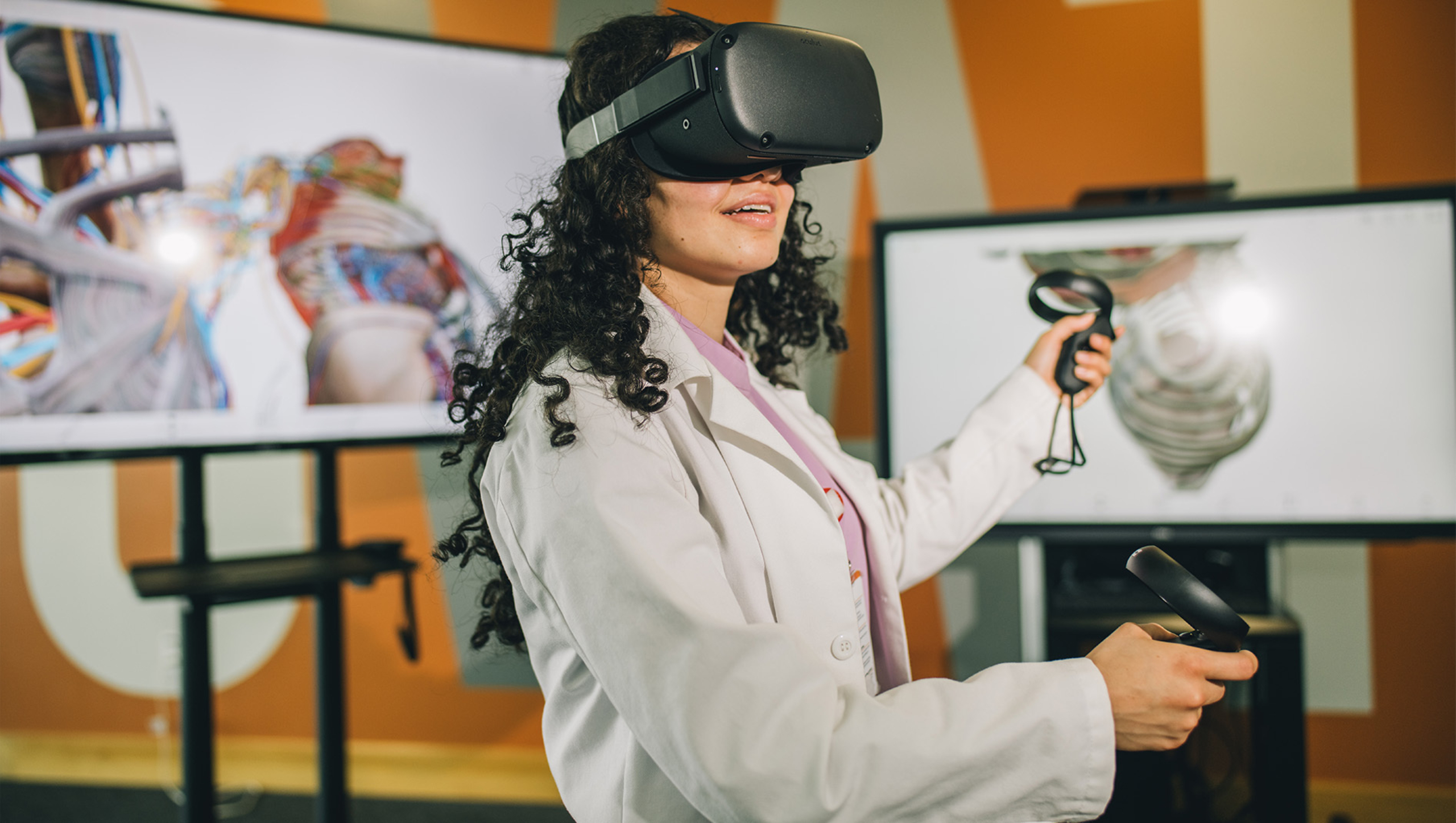 A Dell Medical School student wears a virtual reality headset and accompanying handheld devices to view and manipulate medical imaging.