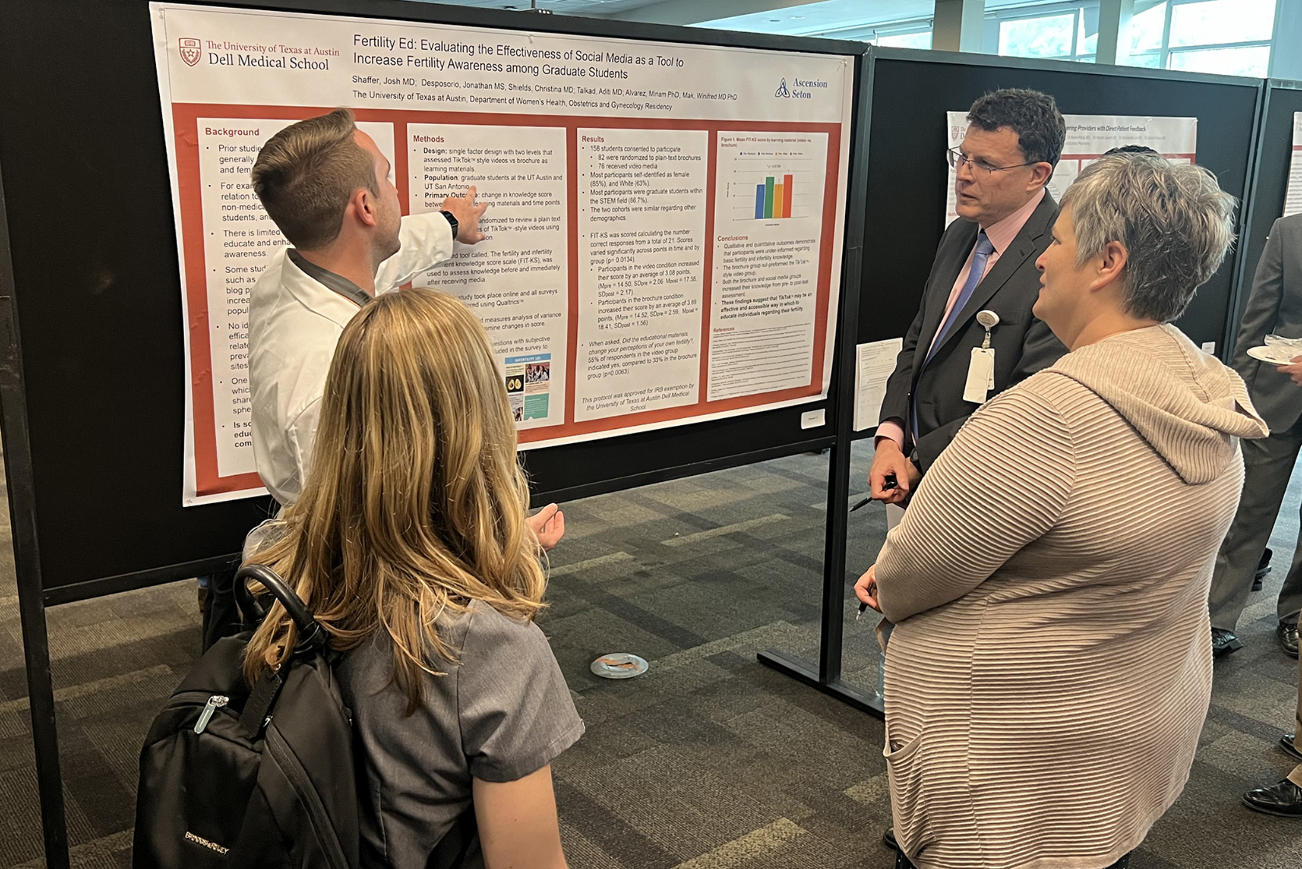 A resident presents his research poster to the judges at resident research day.