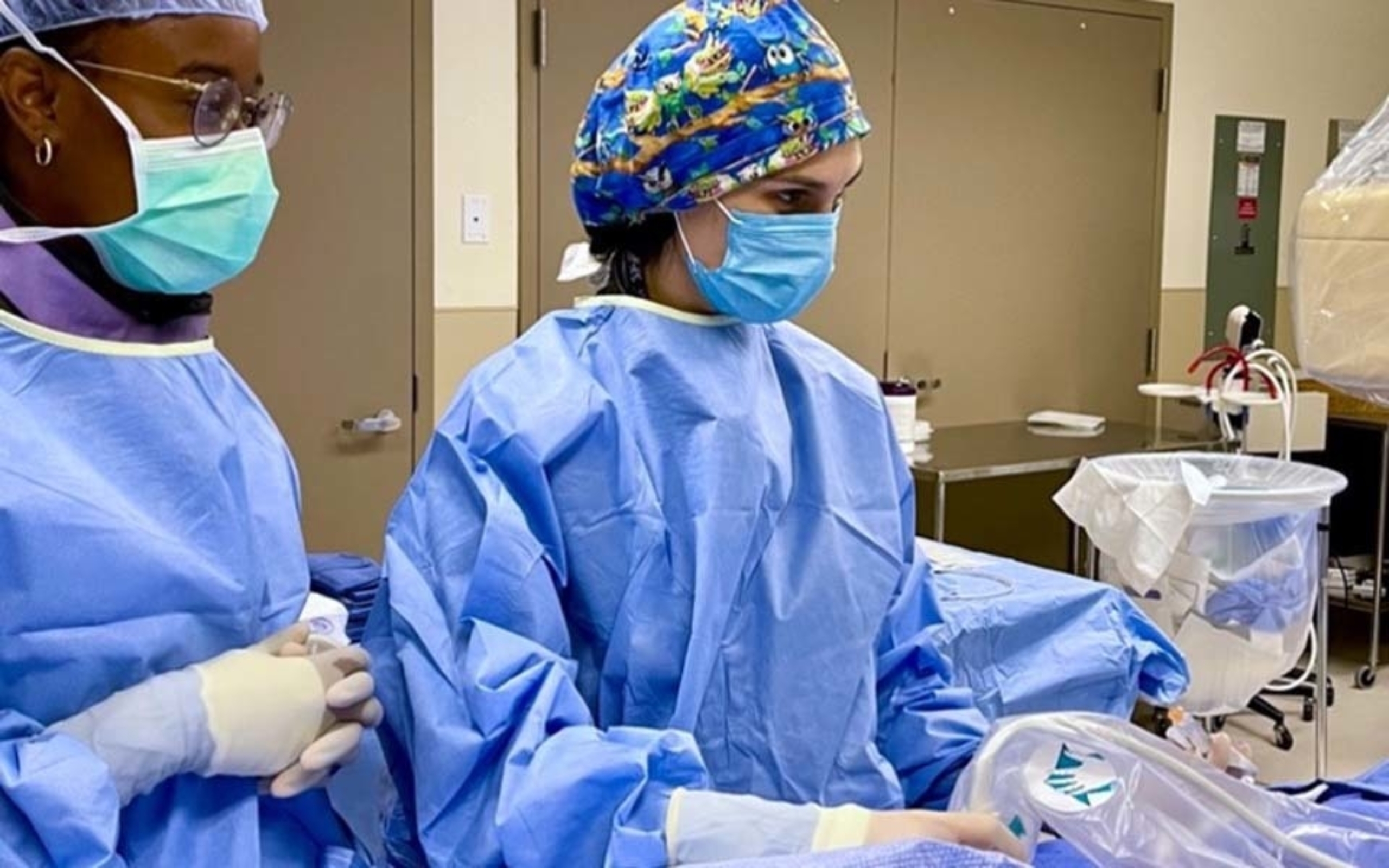 Two women surgeons performing a procedure in an operating room.