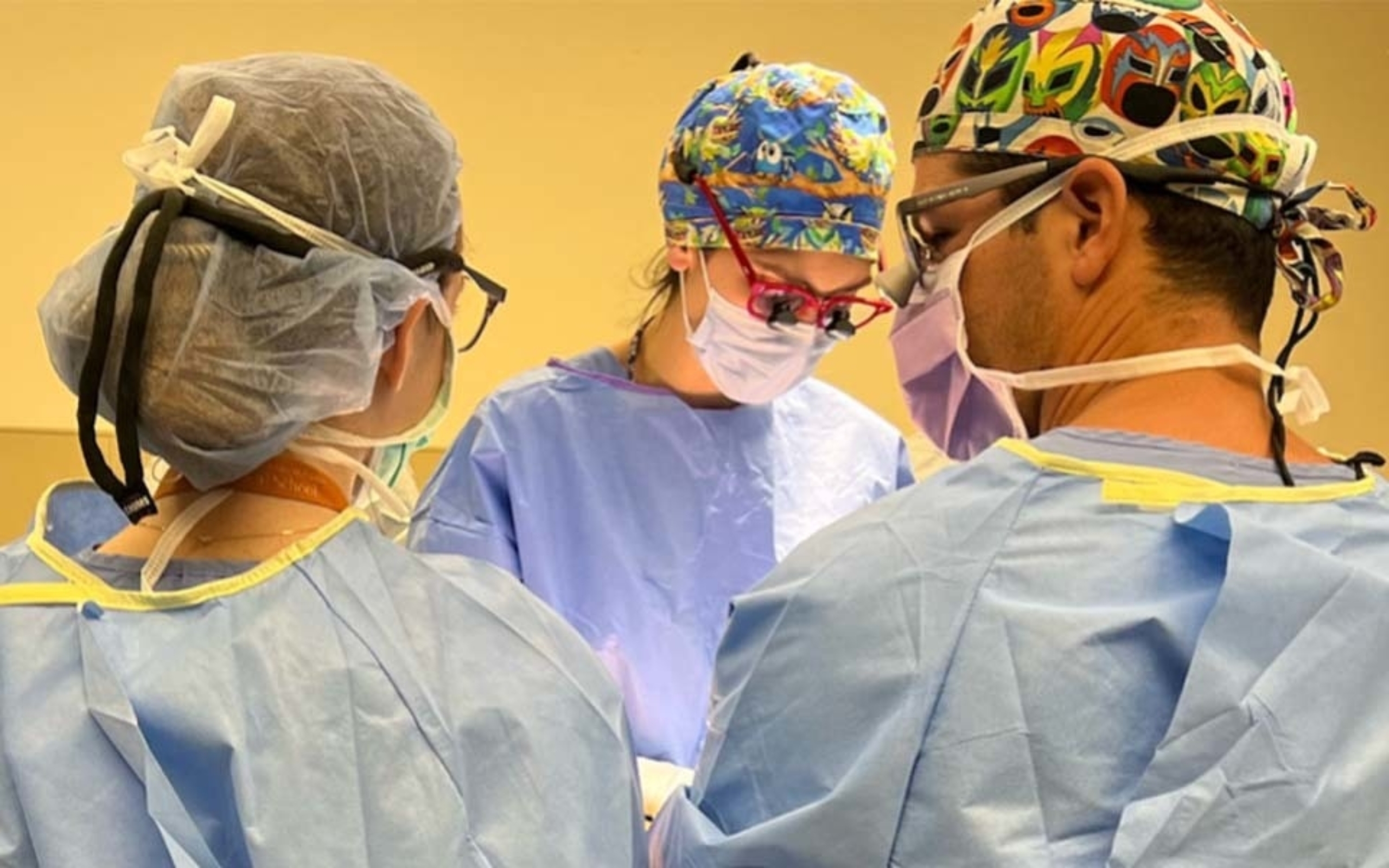 Three surgeons performing a procedure in an operating room.