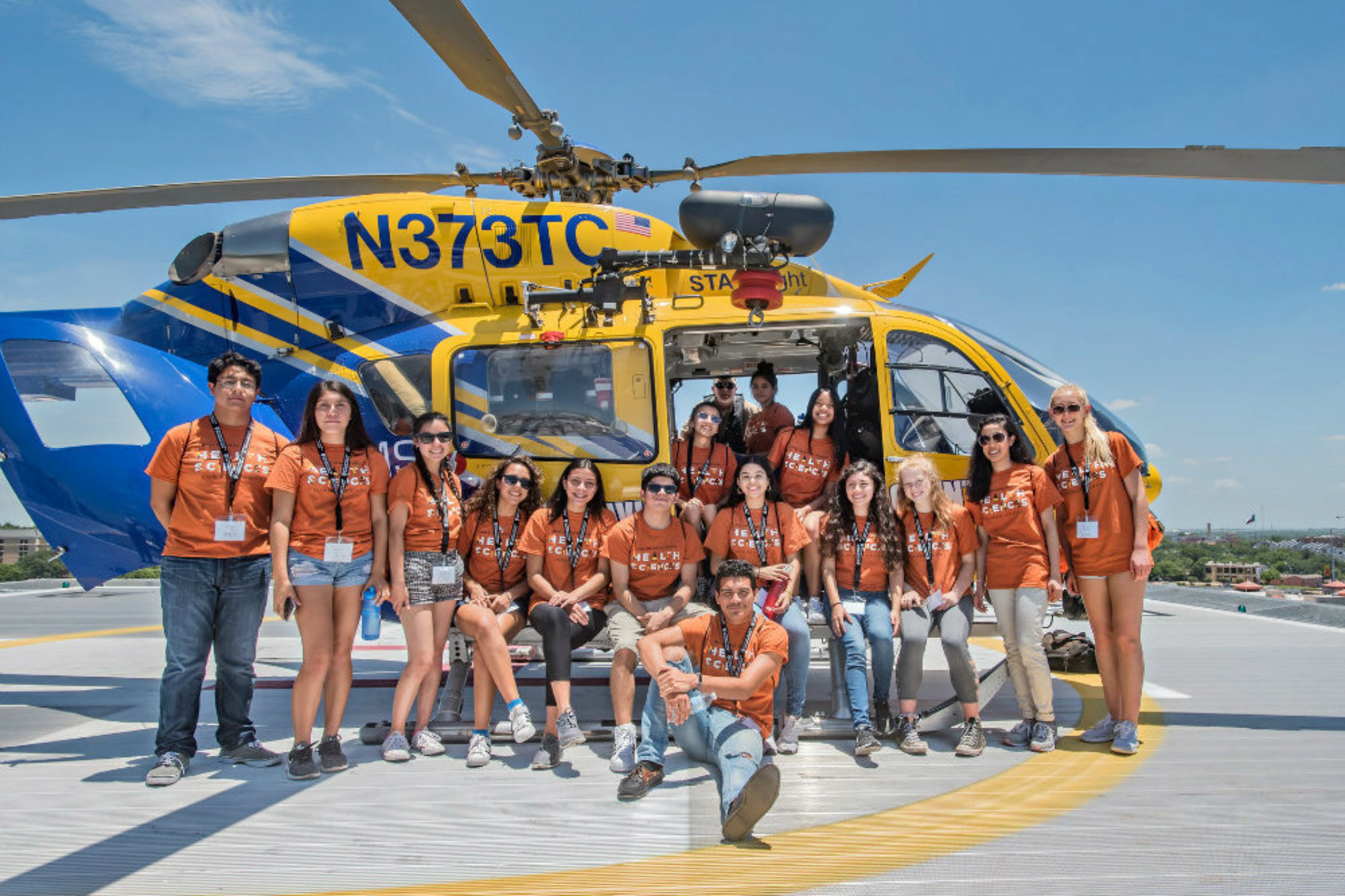 Summer camp participants pose in front of a STAR Flight helicopter