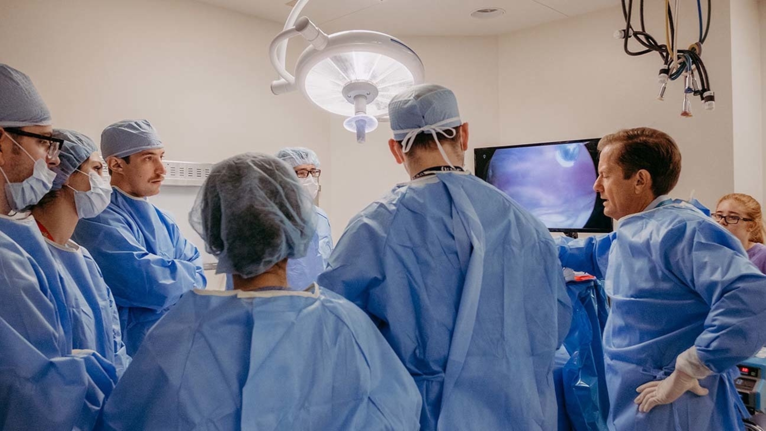 A group of surgeons gather around an operating table for a discussion.