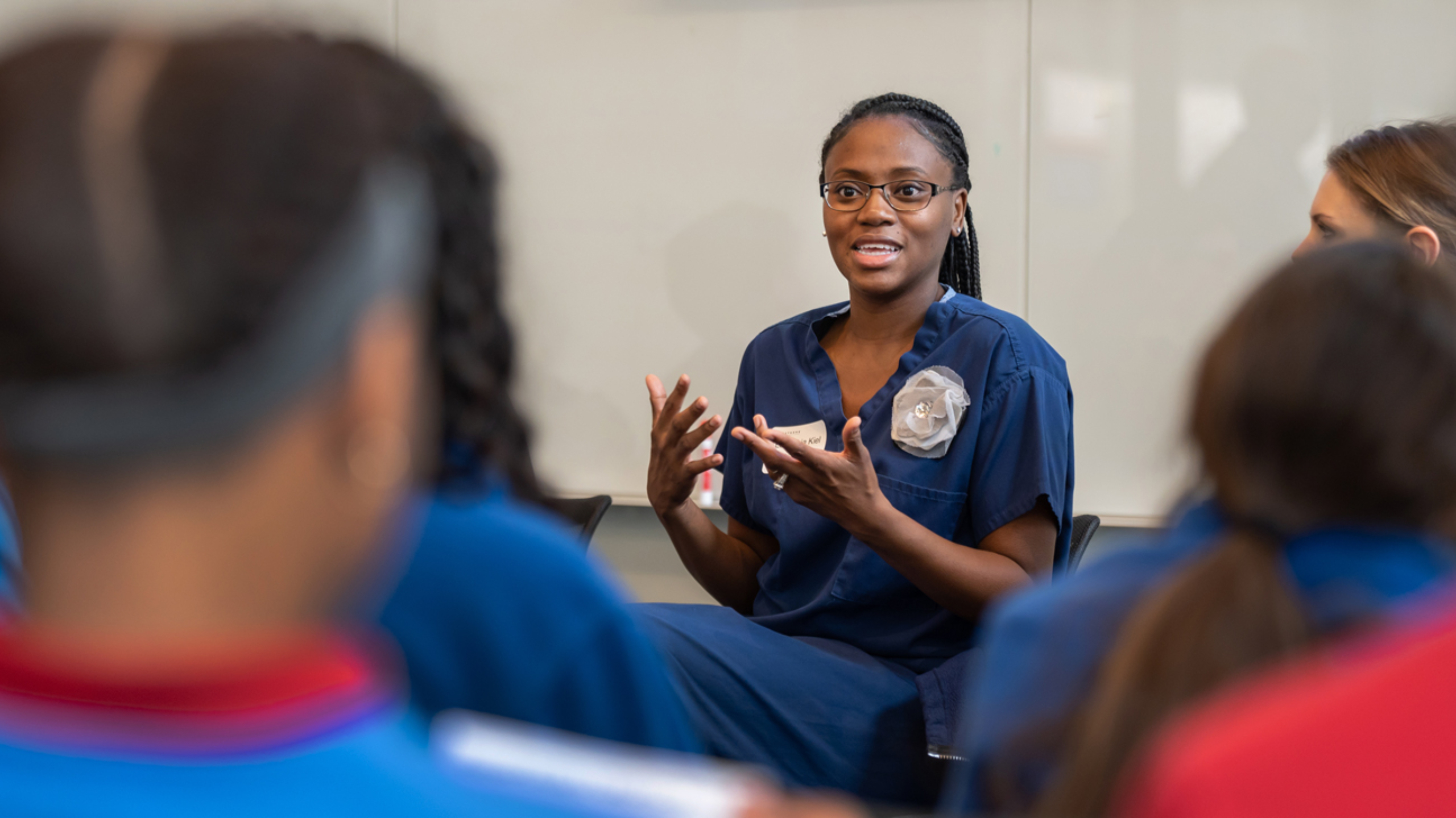 A female Dell Med student speaking in front of a group of middle schoolers.