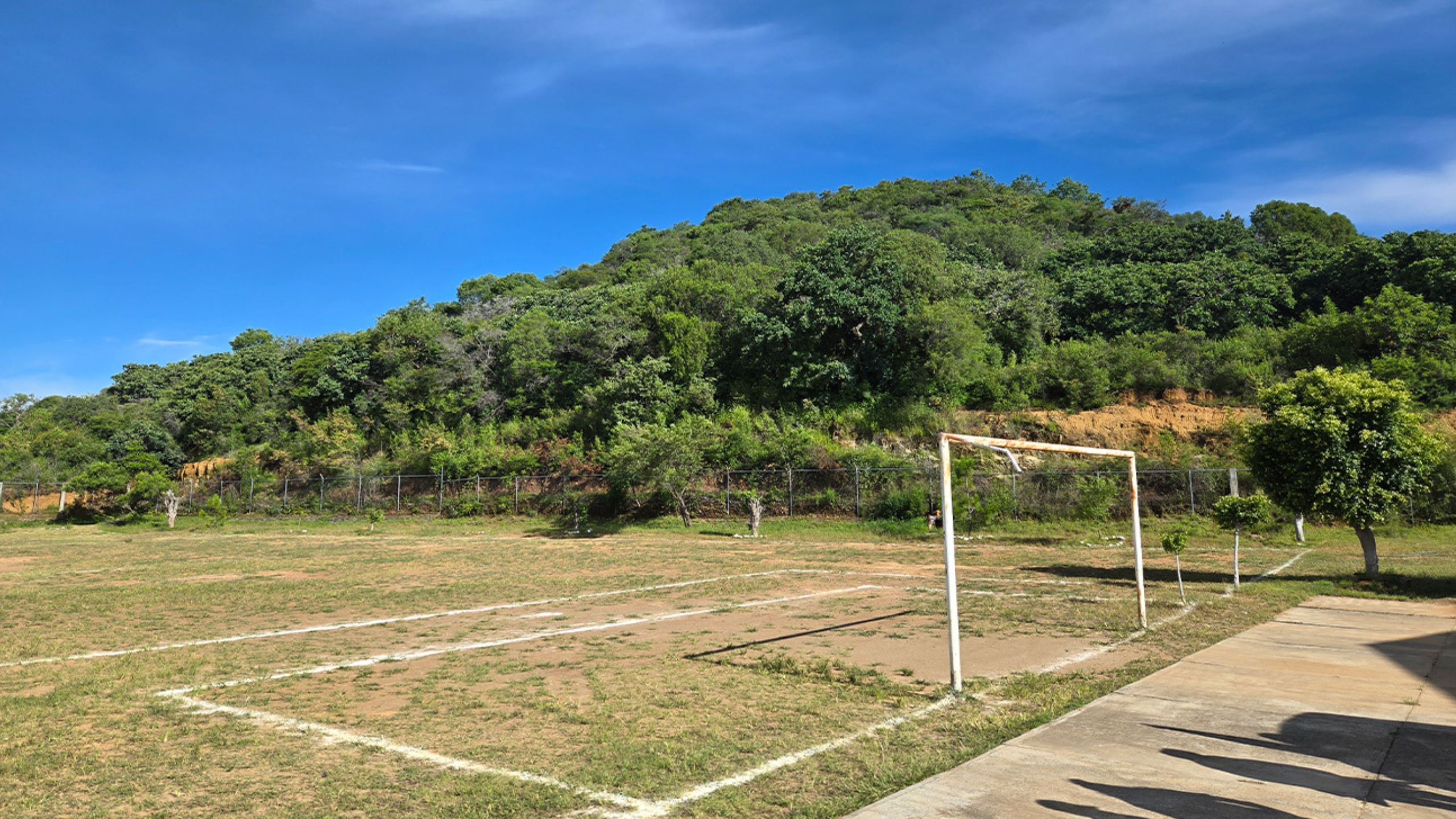 An unoccupied soccer field near Puebla, Mexico, with hills and trees in the background.