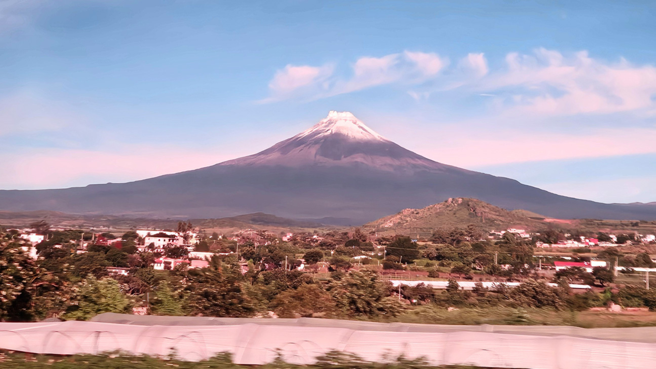 A distant volcano occupies the background of a village skyline.